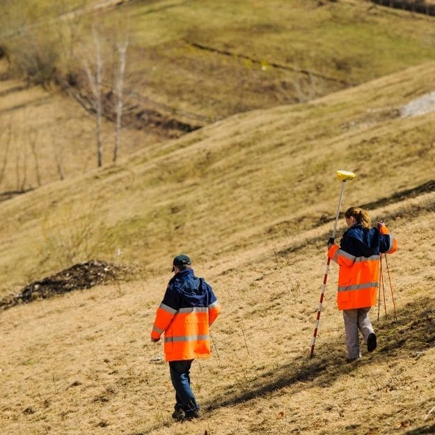 2 workers preparing to survey land